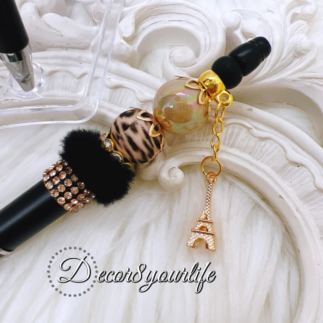 Set of elegant beaded pens with black and gold beads, adorned with charms. Perfect for gifts and personal use.
