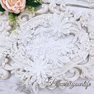 White embroidered floral appliques with detailed lace design on a decorative background