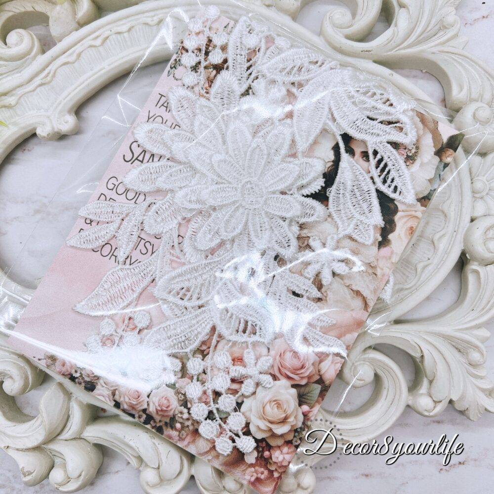 White embroidered floral appliques with detailed lace design on a decorative background