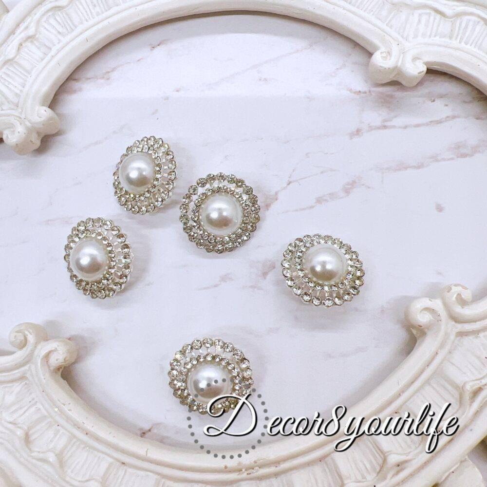 Elegant rhinestone buttons with flat-back pearl centers displayed on a shabby chic frame. Ideal for sewing and crafting projects.