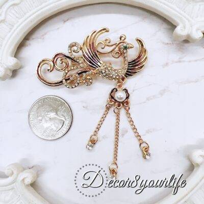 Phoenix Rhinestone Brooch for DIY wedding crafts and elegant bridal decor, featuring gold-tone metal, rhinestones, pearl accents, and dangling chains.