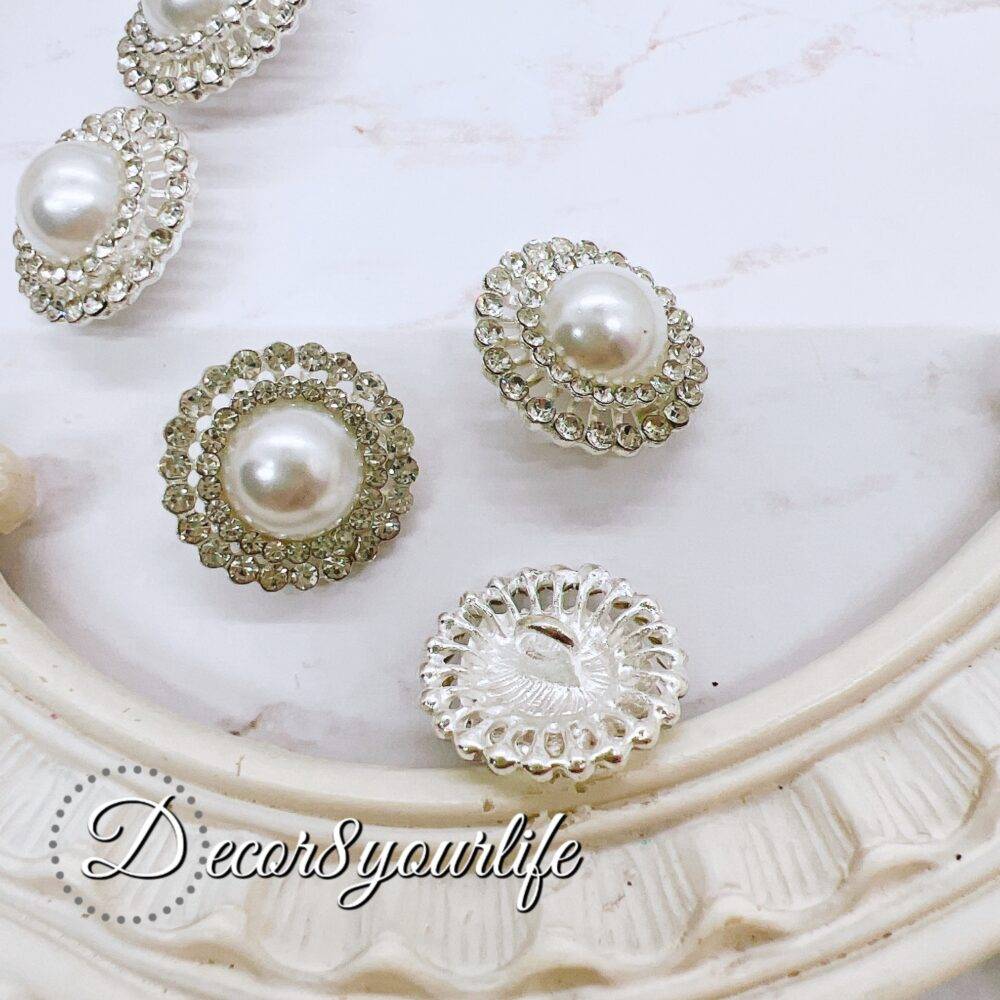 Elegant rhinestone buttons with flat-back pearl centers displayed on a shabby chic frame. Ideal for sewing and crafting projects.