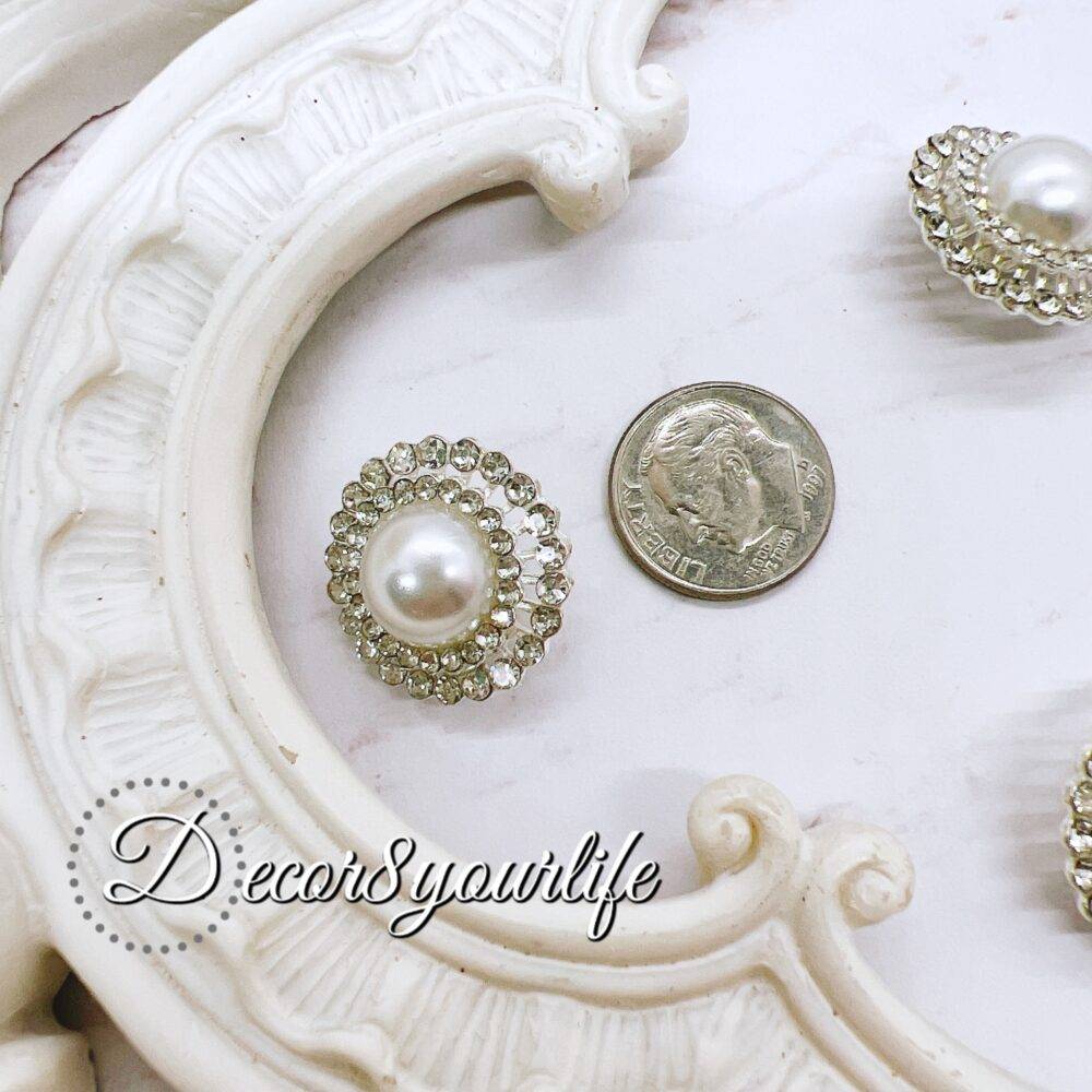 Elegant rhinestone buttons with flat-back pearl centers displayed on a shabby chic frame. Ideal for sewing and crafting projects.