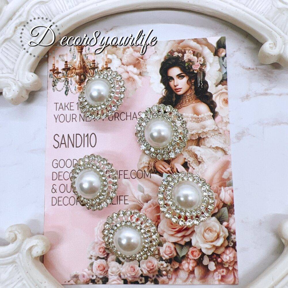 Elegant rhinestone buttons with flat-back pearl centers displayed on a shabby chic frame. Ideal for sewing and crafting projects.