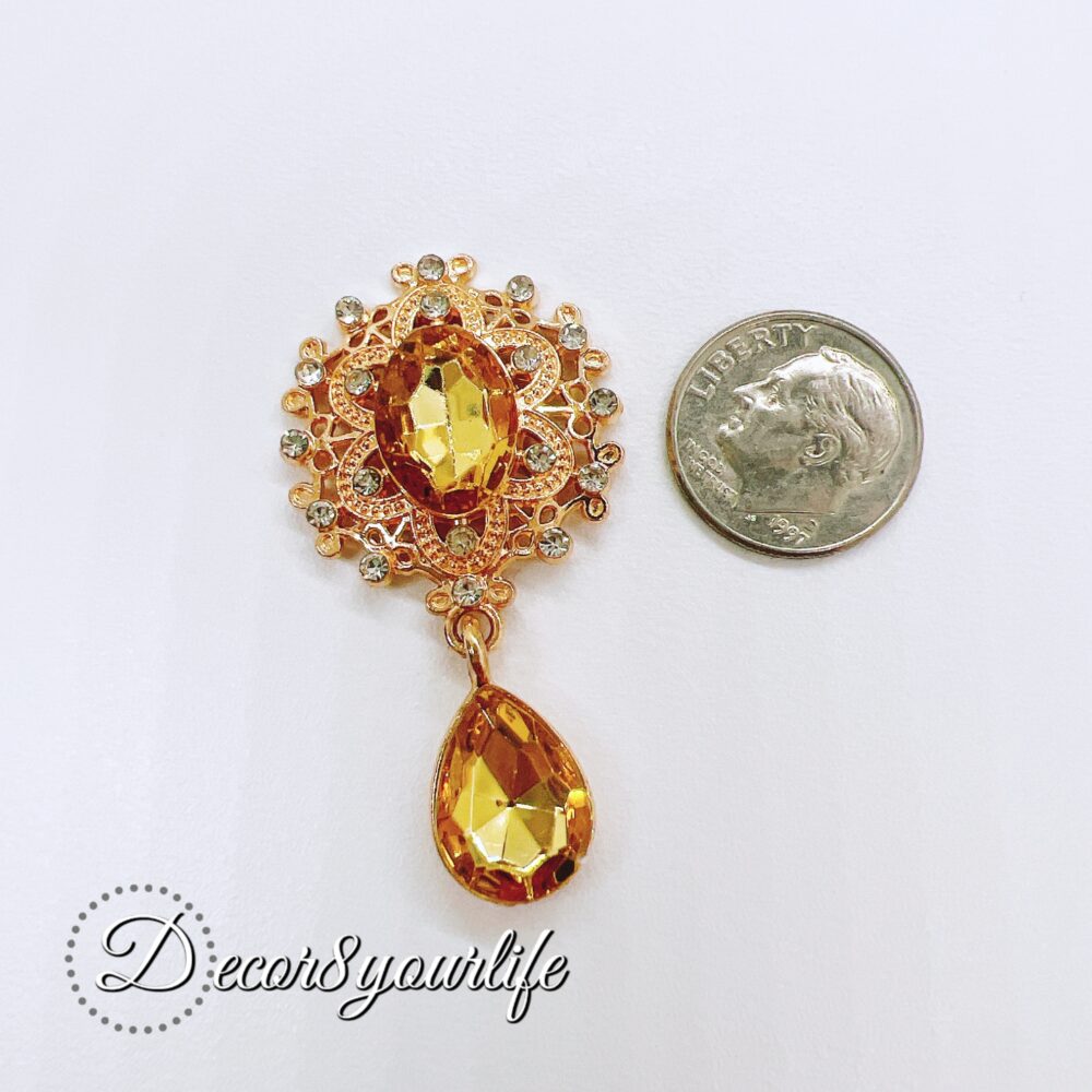 Flat-back brooch embellishment with amber gemstone and rhinestone accents, featuring a teardrop crystal and intricate gold-tone metal detailing, perfect for crafts like scrapbooks, journals, mini albums, and mixed media projects.