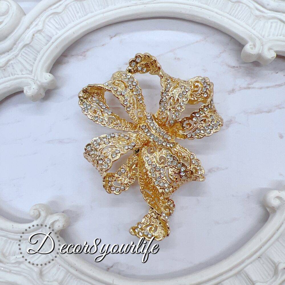 Large Rhinestone Bow Brooch. Large rhinestone bow brooch in gold-tone with intricate detailing, ideal for crafts and bridal decor.