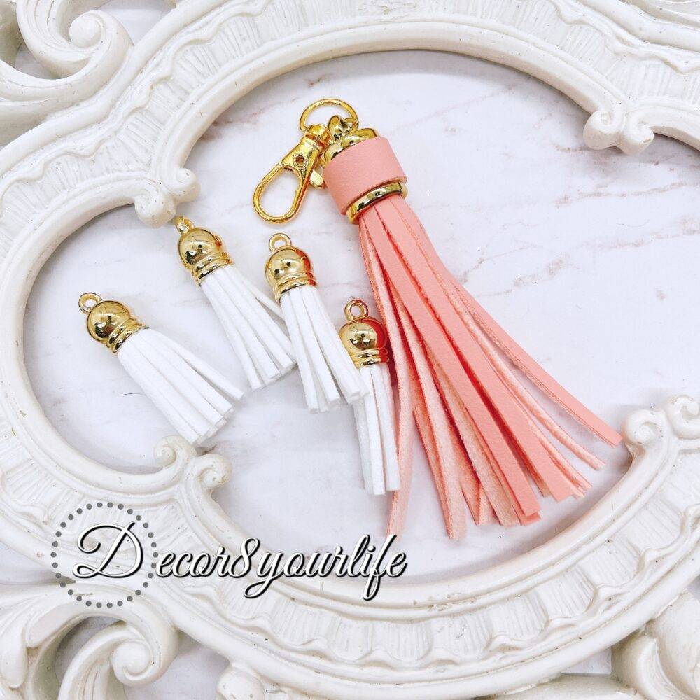 DIY tassel kit with four small white tassels (1.5 inches) and one large pastel peach tassel (3 inches) with a lobster clasp, ideal for crafting projects like scrapbooking, jewelry, and keychains.