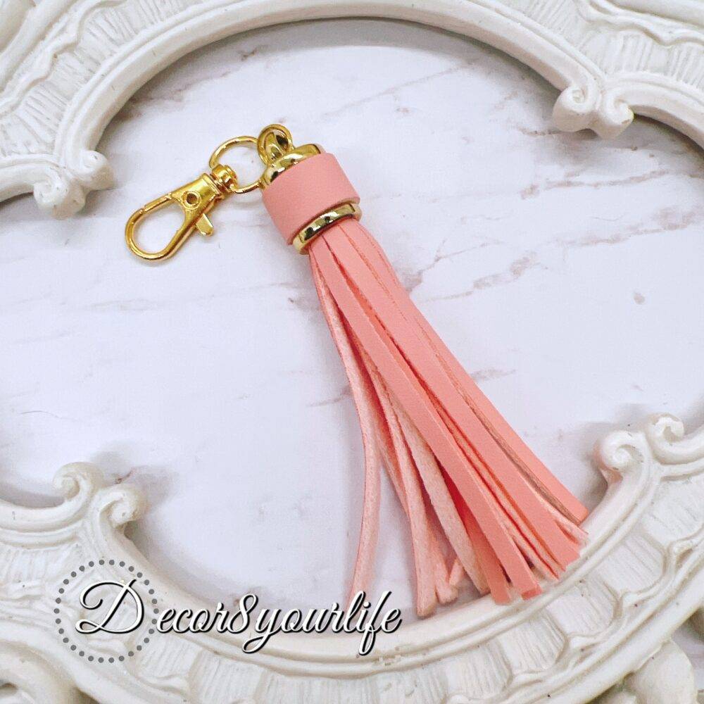 DIY tassel kit with four small white tassels (1.5 inches) and one large pastel peach tassel (3 inches) with a lobster clasp, ideal for crafting projects like scrapbooking, jewelry, and keychains.