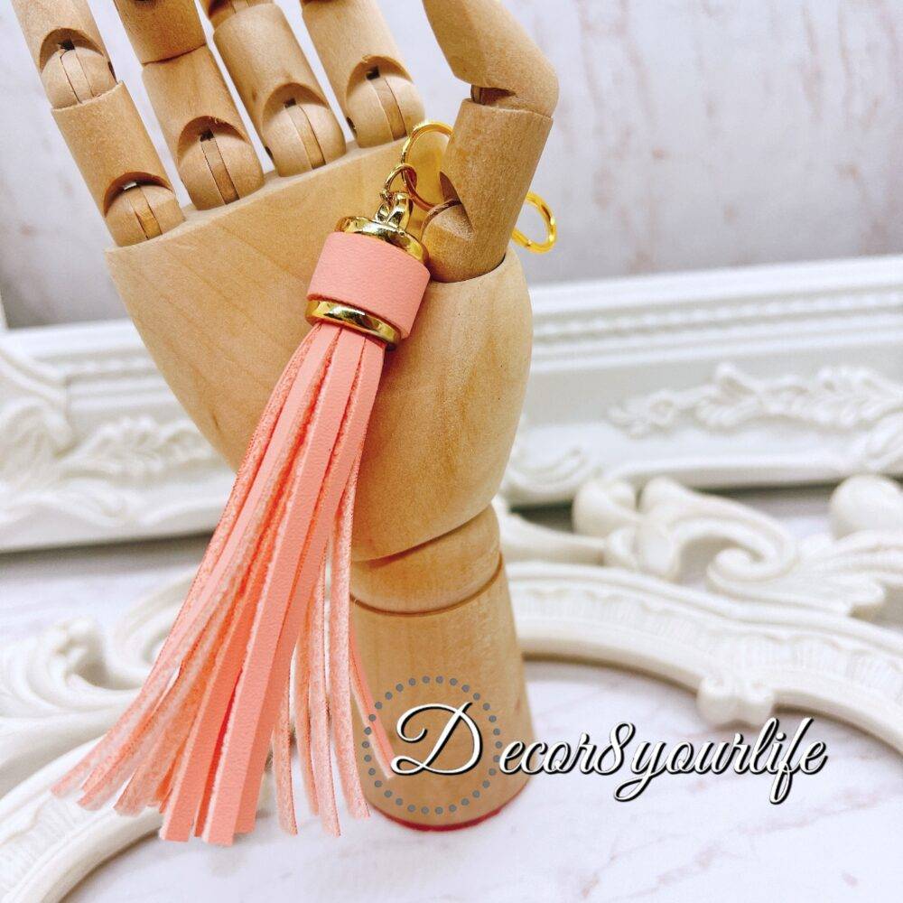 DIY tassel kit with four small white tassels (1.5 inches) and one large pastel peach tassel (3 inches) with a lobster clasp, ideal for crafting projects like scrapbooking, jewelry, and keychains.