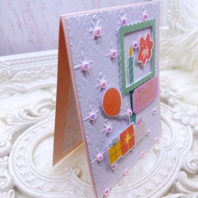 Handmade Greeting Card with Embossed Design and Die-Cut Embellishments.