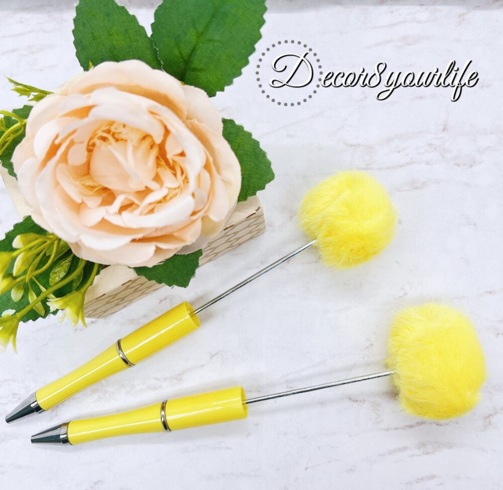 A set of two pastel pom-pom beadable pens featuring a soft, fluffy pom-pom topper and a sleek metal body.