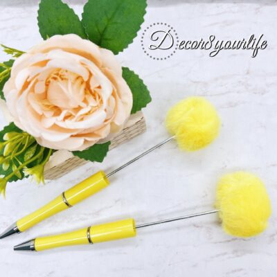 A set of two pastel pom-pom beadable pens featuring a soft, fluffy pom-pom topper and a sleek metal body.