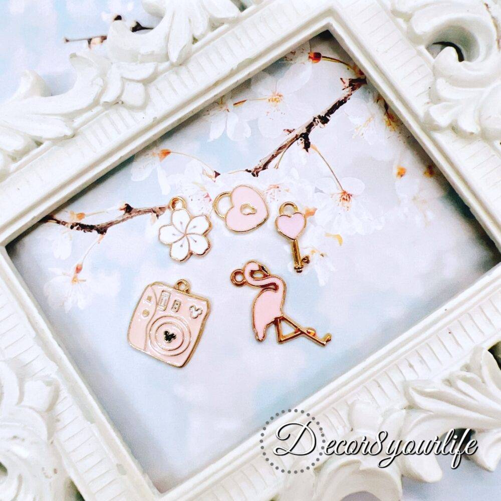 Cute pastel peach and white charm grab bag featuring assorted enamel, and metal charms in floral, heart, and camera designs—perfect for DIY jewelry and crafts.