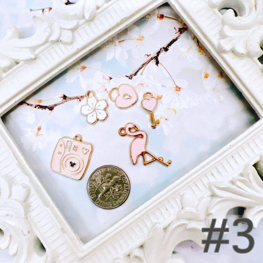 Cute pastel peach and white charm grab bag featuring assorted enamel, and metal charms in floral, heart, and camera designs—perfect for DIY jewelry and crafts.