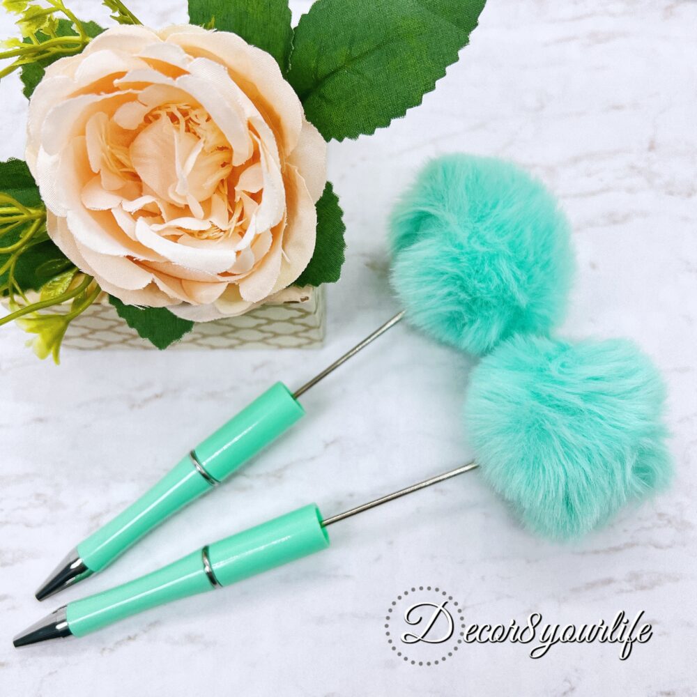 A set of two pastel pom-pom beadable pens featuring a soft, fluffy pom-pom topper and a sleek metal body.