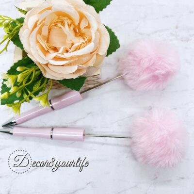 A set of two pastel pom-pom beadable pens featuring a soft, fluffy pom-pom topper and a sleek metal body.