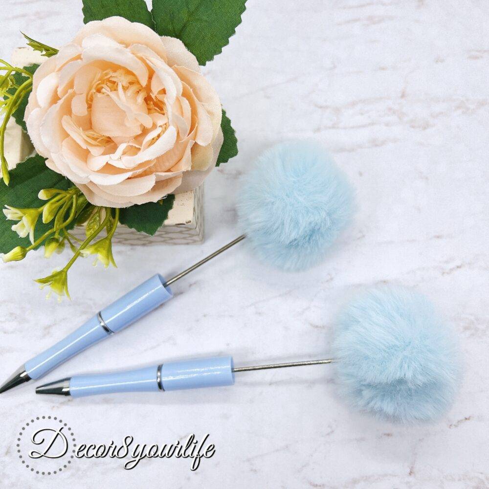 A set of two pastel pom-pom beadable pens featuring a soft, fluffy pom-pom topper and a sleek metal body,