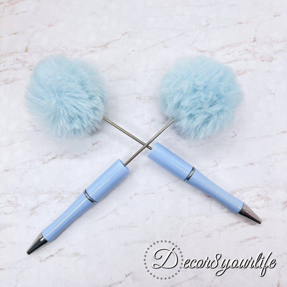 A set of two pastel pom-pom beadable pens featuring a soft, fluffy pom-pom topper and a sleek metal body,