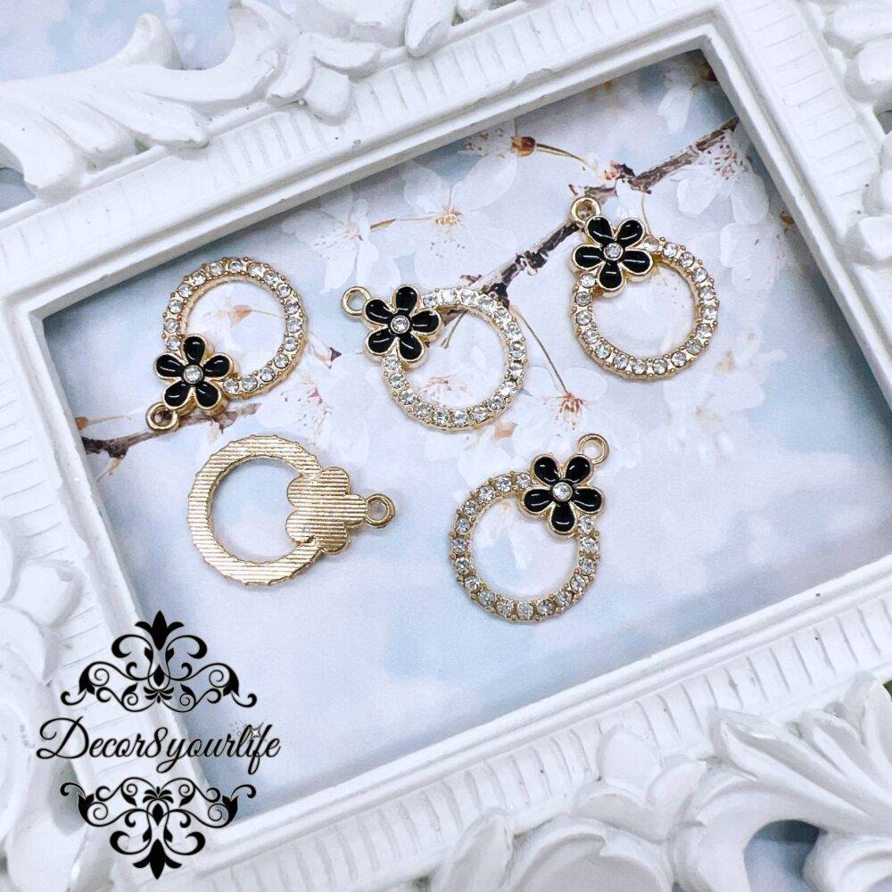 Set of five black enamel rhinestone charms displayed in a vintage white frame, perfect for DIY jewelry and craft projects.