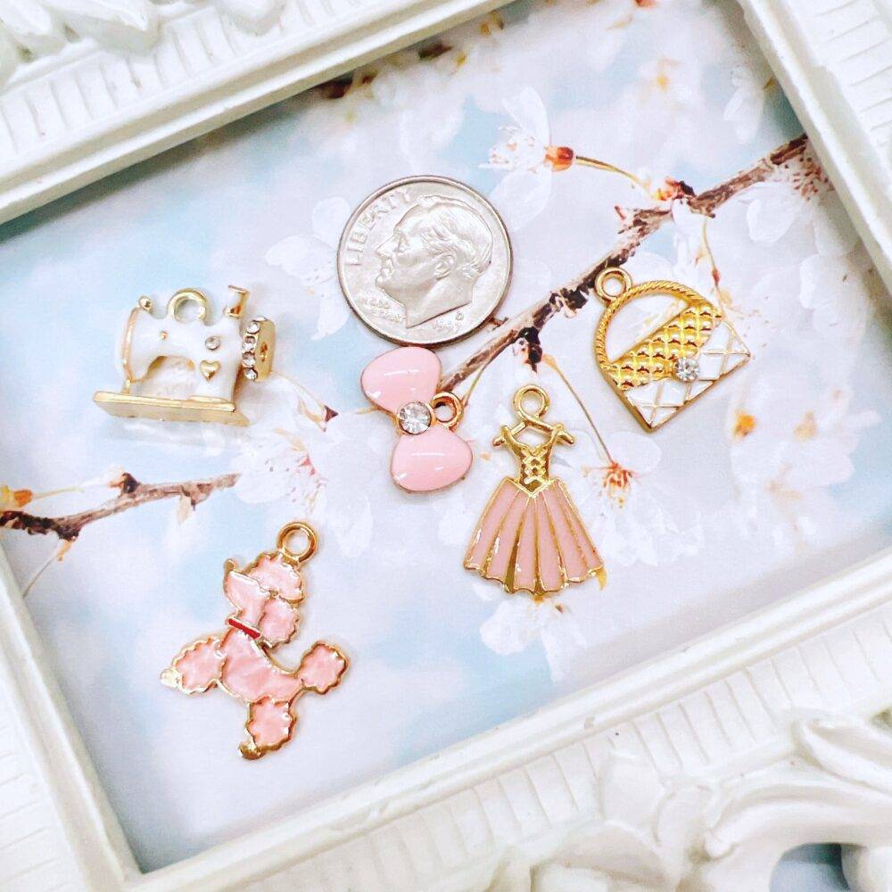 Elegant pink and white charm grab bag featuring assorted enamel, resin, and metal charms in floral, heart, and sewing-themed designs—perfect for DIY jewelry and crafts.