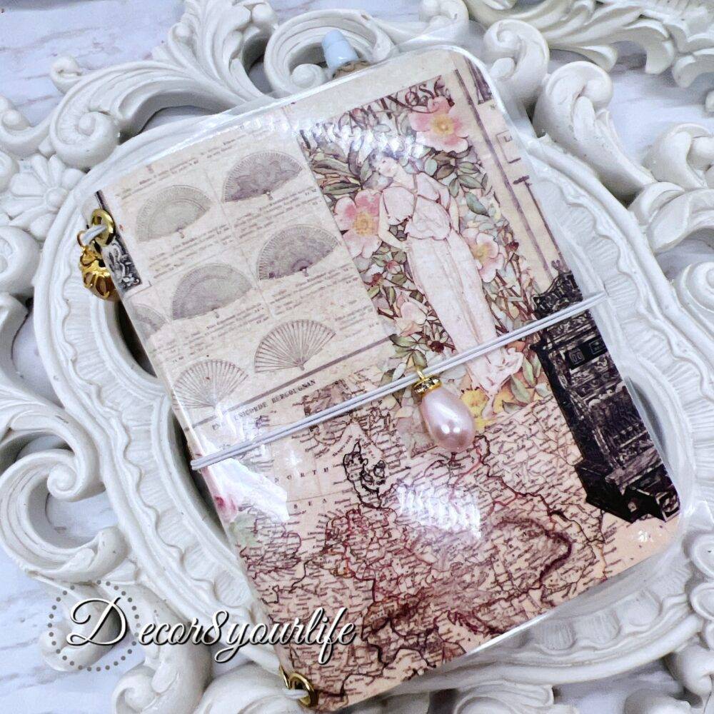 There’s something magical about putting pen to paper, and this shabby chic traveler's notebook makes it even more special! Handcrafted with love, it features two altered mini composition notebooks, a handy pocket for essentials, and the cutest beaded pen to match.