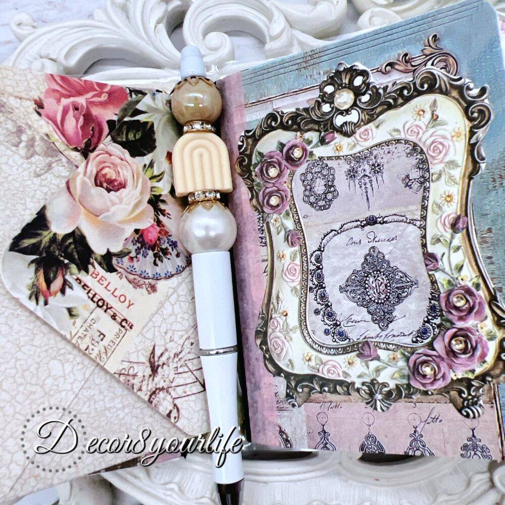 There’s something magical about putting pen to paper, and this shabby chic traveler's notebook makes it even more special! Handcrafted with love, it features two altered mini composition notebooks, a handy pocket for essentials, and the cutest beaded pen to match.