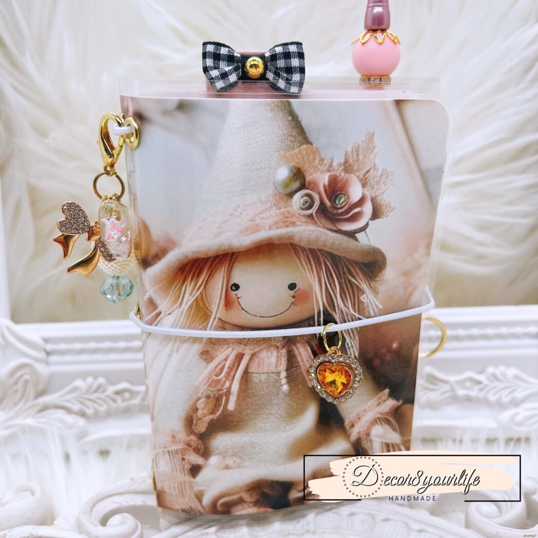 Handmade laminated traveler’s notebook with exclusive paper design, beaded pen, charms, and altered mini notebooks.