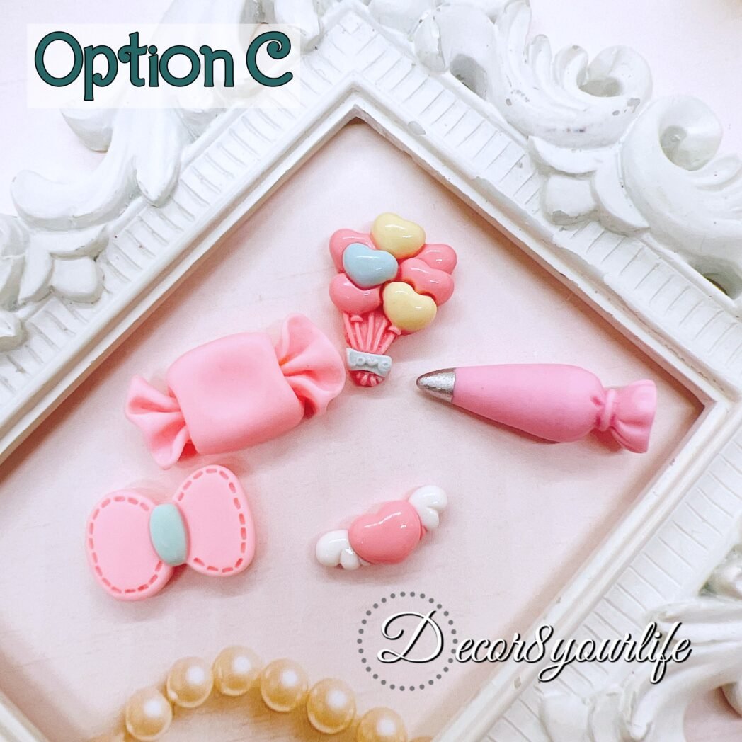 Close-up photo of assorted pink flat-back cabochons. The cabochons include bow shapes, candy shapes, and character accents. These resin embellishments are sold in a 5-pack and can be glued to planner dashboards, mini albums, hair bows, shaker key-chains, and gift tags.