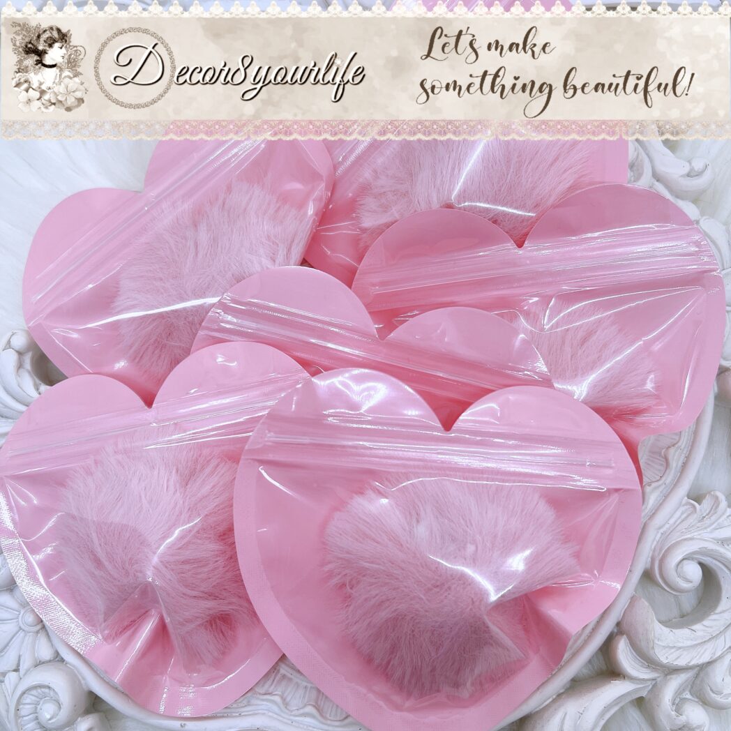 Close-up of blush pink faux fur pom pom with loop attachment for DIY projects