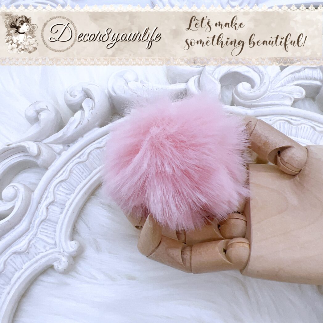 Close-up of blush pink faux fur pom pom with loop attachment for DIY projects