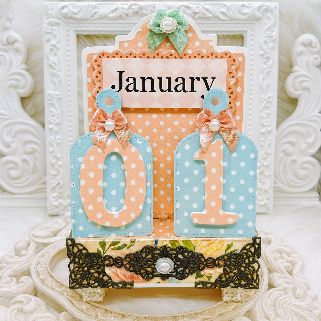 Handmade perpetual desk calendar set to January 01 with pastel polka dot tags, satin bows and lace trim in a shabby chic white frame setting.