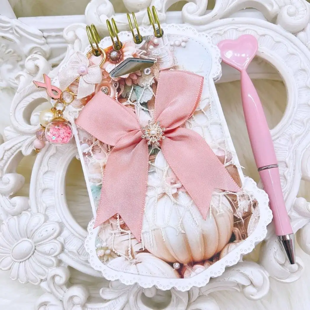 shabby chic pocket journal with blush satin bow, pearl brooch, white pumpkin artwork, ornate die-cut edges, gold-tone coil, pink heart pen, removable charm