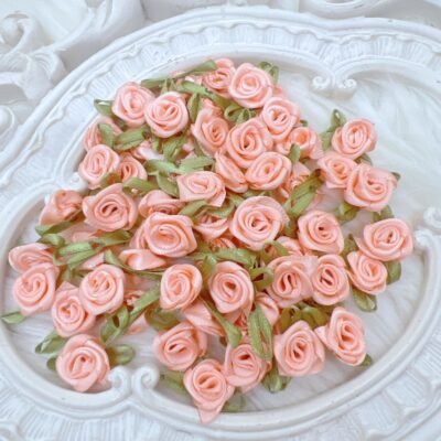 Small satin ribbon rose embellishments in a pastel peach color. You may use these embellishments in crafts like scrapbooks, journals, cards, diy home decor, bridal crafts.