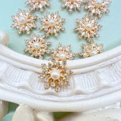 Gold tone alloy snowflake flat back cabochon embellishment approximately half inch with pearl center