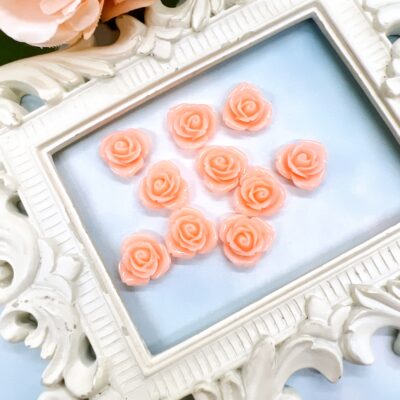 resin flower embellishments with peach centers displayed on soft blue background inside ornate white vintage frame