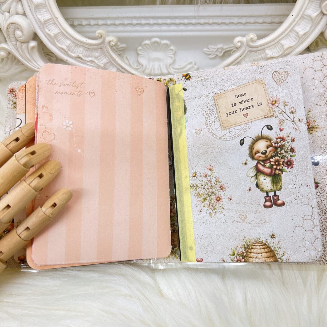 Open Honey Bees & Summer Breeze handmade micro traveler's notebook showing two altered mini composition notebooks, transparent storage pocket, handmade folders, bookmarks, and coordinating bee-themed papers.