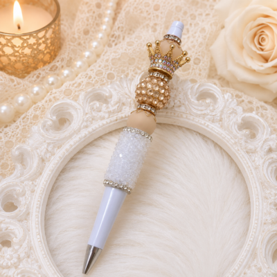 Handmade Luxury Beaded Crown Pen featuring a champagne pavé rhinestone bead, White Rock Candy bead, jeweled gold crown topper, white barrel, gold accents, and sparkling crystal details.