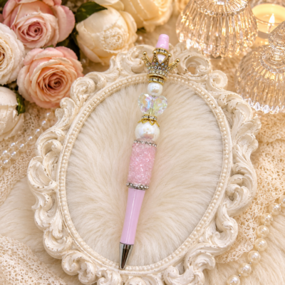 Handmade blush pink refillable luxury pen with crystal crown topper, iridescent heart bead, pearl accents, pink Rock Candy accent, and polished silver hardware.