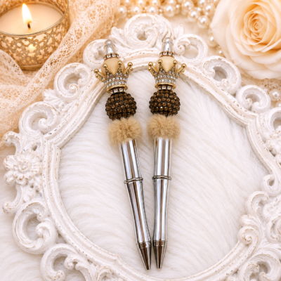 Handmade luxury faux fur crown pen featuring a polished silver-tone barrel, sparkling chocolate rhinestone bead, champagne faux fur accent, ivory designer bead, jeweled gold crown topper, and refillable black ink.