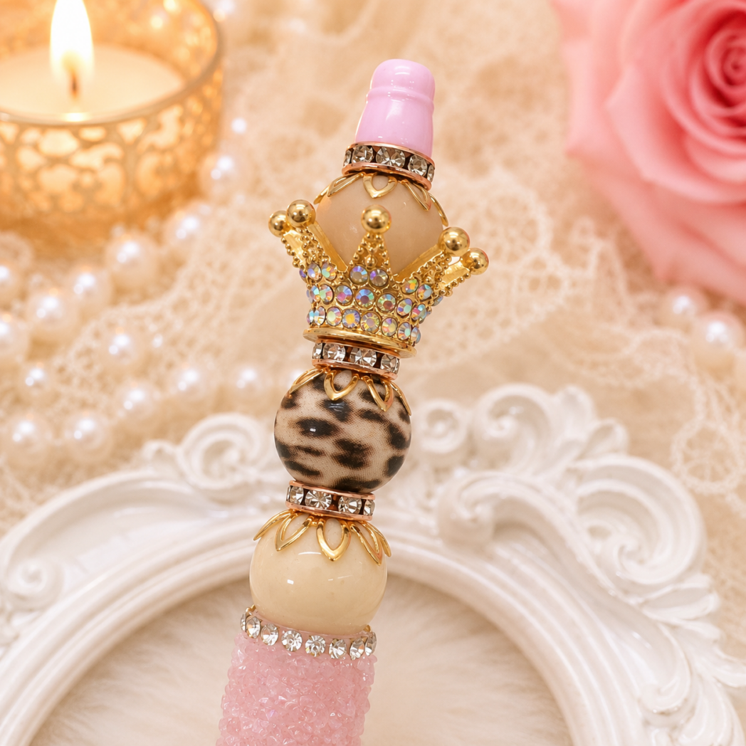 Close-up of a handmade boutique-style beaded pen featuring leopard print focal bead, gold PandaHall crown topper, rhinestone spacers, and ivory accent beads.
