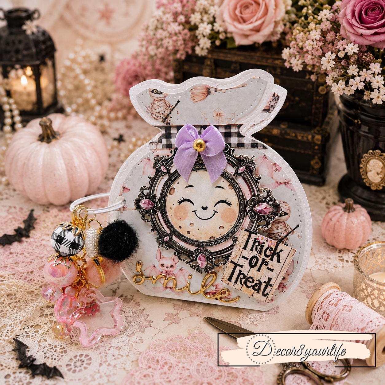 Handmade Halloween treat bag shaped notebook decorated with exact Decor8yourlife pastel Halloween scrapbook paper, featuring cute pink bats, mummies, whimsical characters, a black and white gingham bow, pink gem embellishments, and a layered “Trick or Treat” design with a decorative beaded charm.